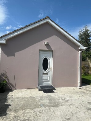 A building with a white door and a small porch area. - The Little Grove, one bedroom studio; cosy, stylish, peaceful, and central. (Tralee)