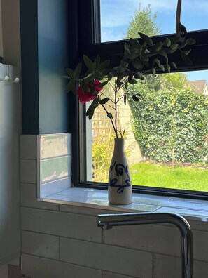 A window sill with a vase containing a plant and flowers. - The Little Grove, one bedroom studio; cosy, stylish, peaceful, and central. (Tralee)