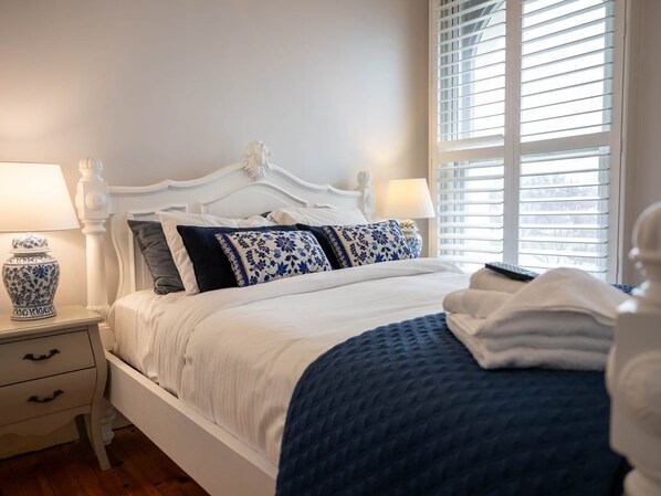 A bed with a white headboard, a blue and white patterned pillow, and a blue blanket. - Deck Quarters-Westwing (Mansfield)