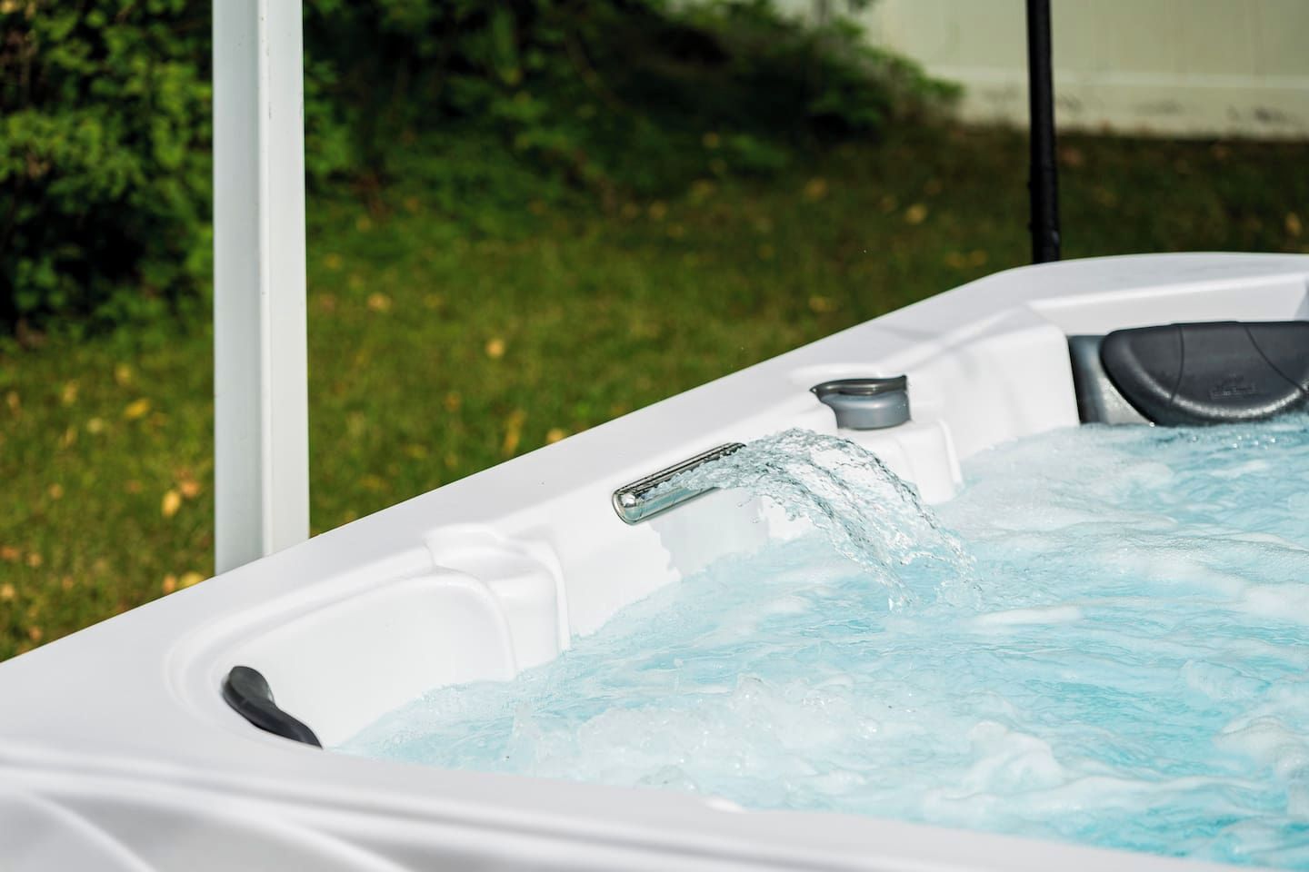 Un bain à remous dont l’eau déborde, entouré de verdure.