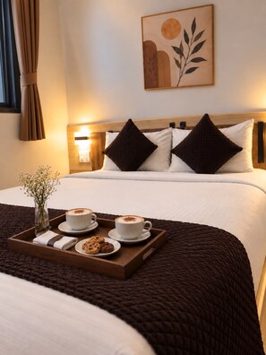 A hotel room with a bed, a tray with coffee and cookies, a vase with flowers, and a wall art piece. - hotel Neelam Executive  (Rajgurunagar)