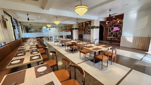 Een restaurant met verschillende eetgedeeltes, waaronder zitjes en tafels met stoelen.