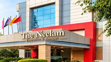 Ein Hotel mit einer modernen Fassade, einem auffälligen 'N'-Logo und der Bezeichnung 'The Neelam Executive & Banquet'.