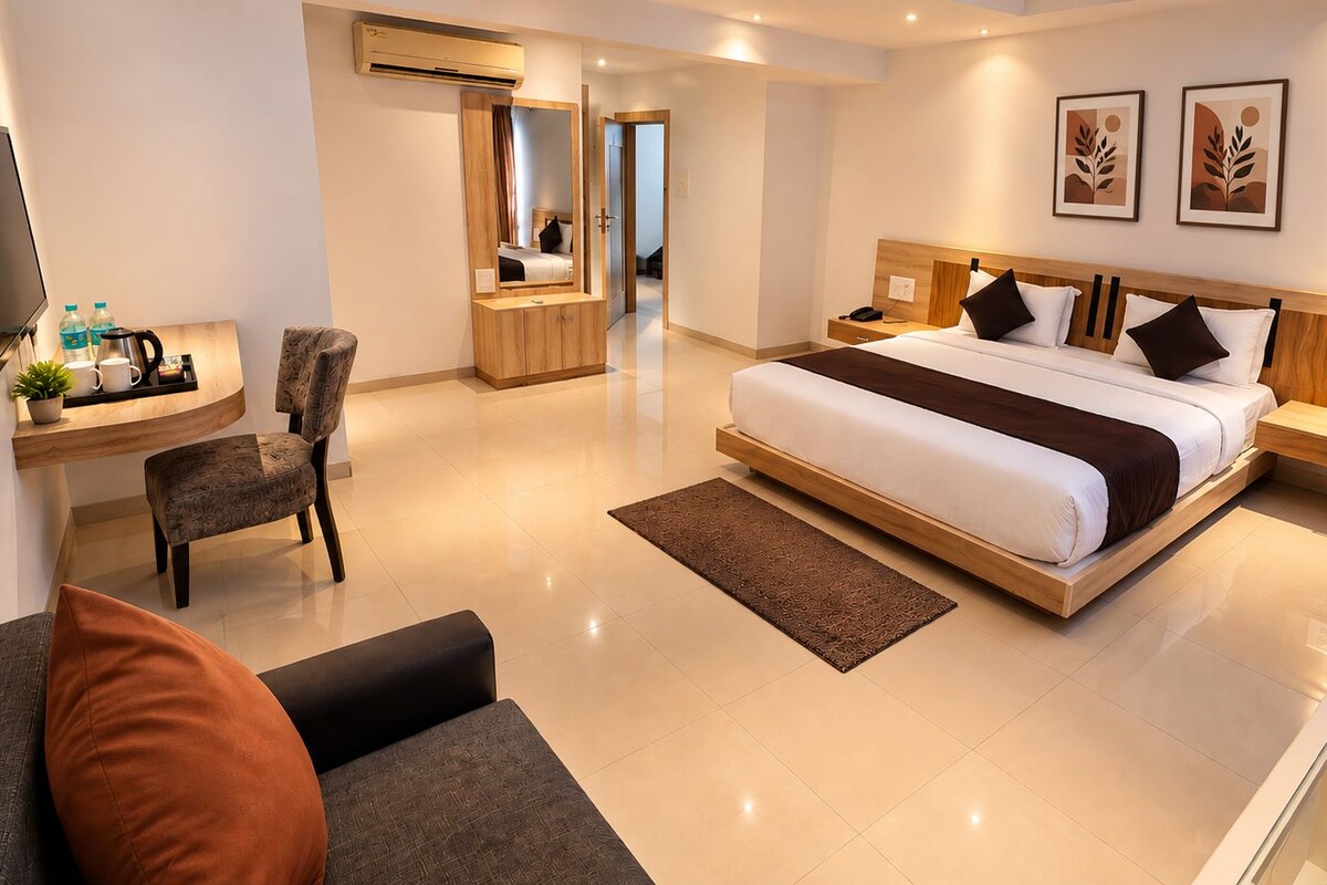A modern hotel room with a large bed, a desk, a chair, and a television.