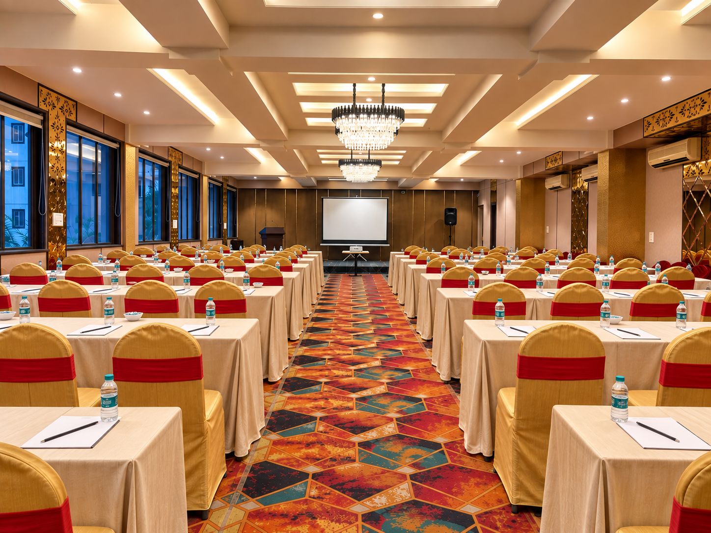 A conference room with rows of tables, chairs, and a projector screen.