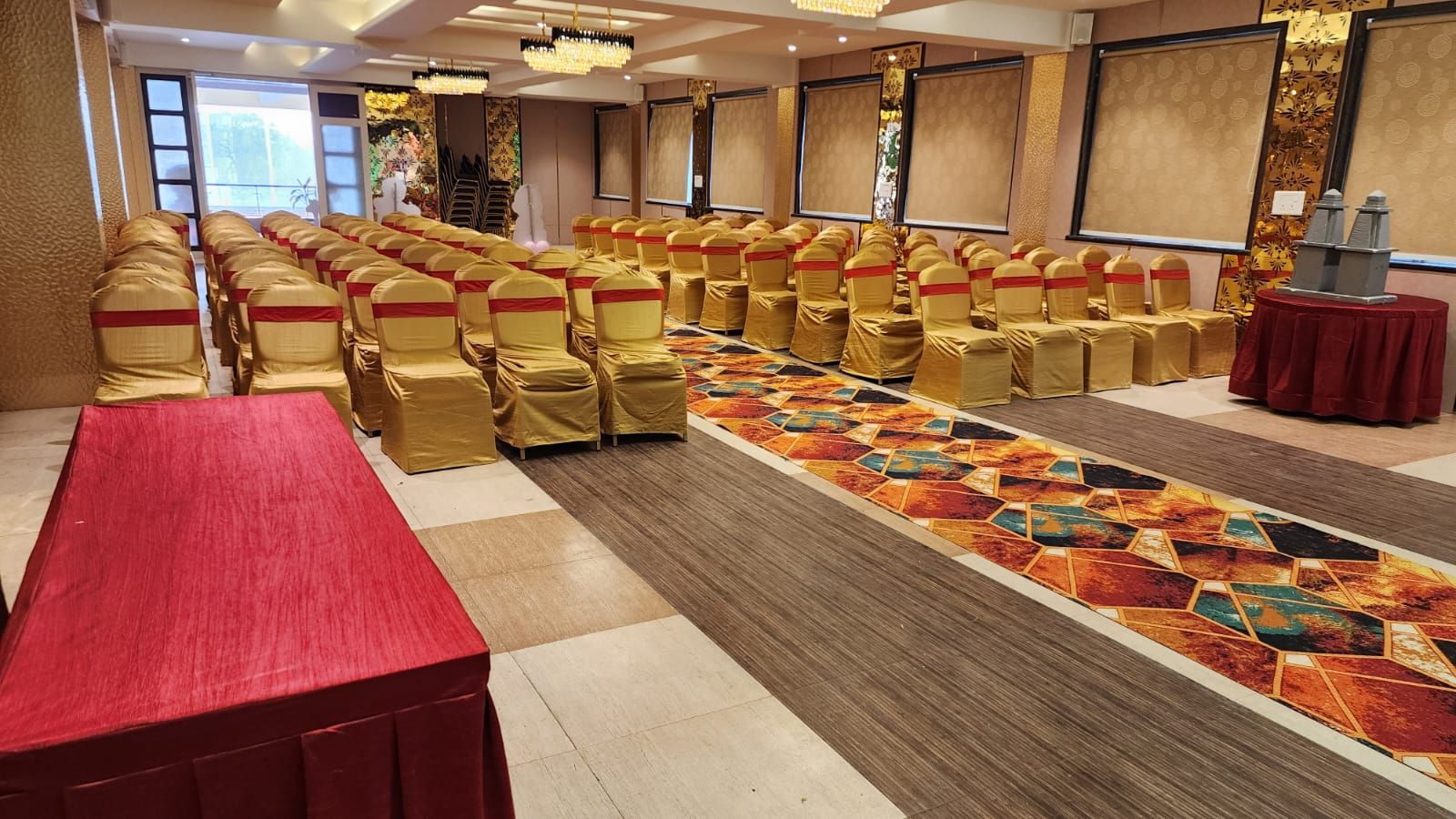 A conference room with rows of chairs, a long table, and a patterned carpet.