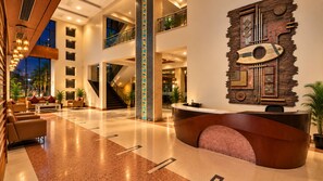 A spacious lobby with a reception desk, seating area, and a staircase leading to upper floors.