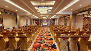 Un salón de conferencias con filas de sillas, un escenario y una alfombra estampada.