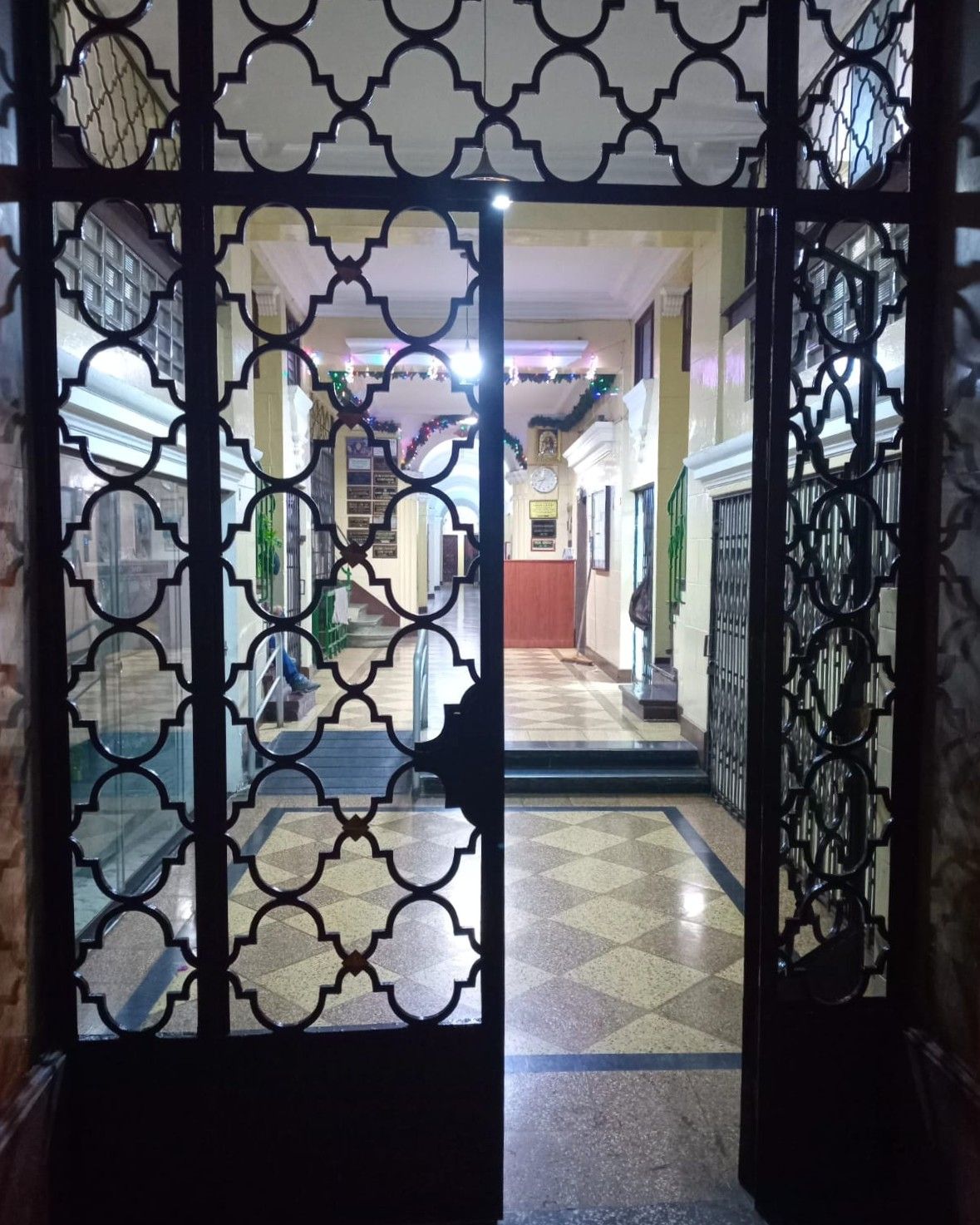 A hallway with a patterned metal gate, tiled flooring, and a staircase leading to an upper level.