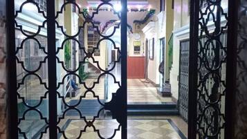 A hallway with a patterned metal gate, tiled flooring, and a staircase leading to an upper level.