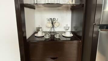 A kitchen with dark cabinetry, a stainless steel refrigerator, and a glassware holder with multiple glasses and cups.