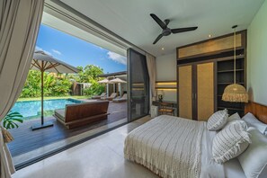 Ein Schlafzimmer mit einem großen Bett, einem Deckenventilator und Blick auf Pool und Garten.