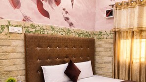 Een hotelkamer met een groot bed, een hoofdeinde, een nachtkastje, een aan de muur bevestigde televisie en een raam met gordijnen.