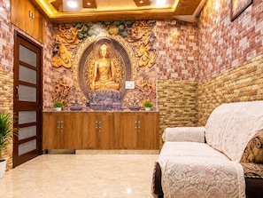A room with a large Buddha statue, wooden cabinets, and a bed.