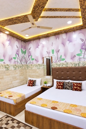 A hotel room with two beds, a ceiling fan, a mirror, and a decorative wall with floral patterns. - Jindal Bed and Breakfast (Amritsar)