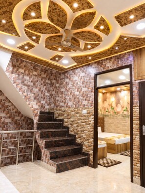 Interior de hotel con escalera, cama y techo decorativo.