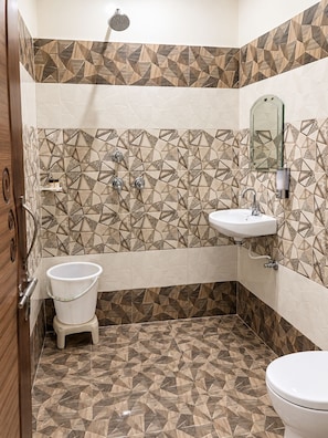 A bathroom with a geometric patterned tile design, a white sink, a toilet, and a shower.
