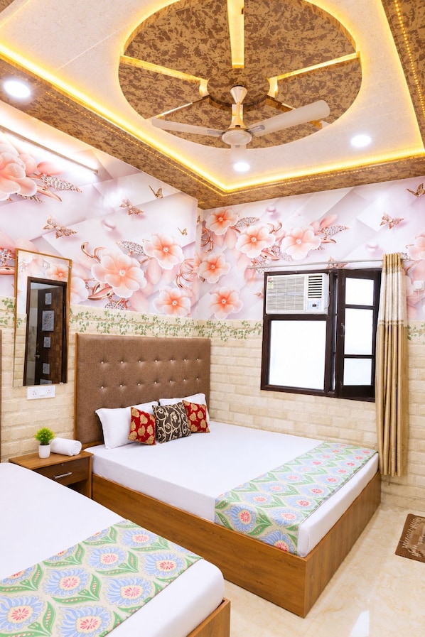 A bedroom with a large bed, a smaller bed, a ceiling fan, and a window with curtains.