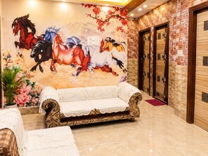 A lobby with a mural of horses, a white sofa, and a wooden door. - Jindal Bed and Breakfast (Amritsar)