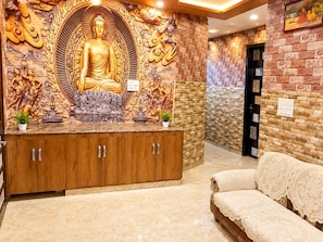 A reception area with a Buddha statue, wooden cabinets, and a brick wall.