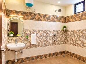 Un baño con lavamanos, espejo, ducha y paredes decoradas con azulejos.