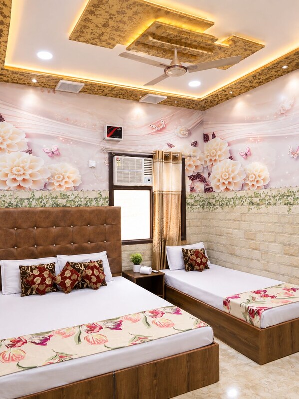 Une chambre d’hôtel avec deux lits, un ventilateur de plafond et des motifs floraux sur les murs.