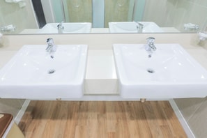 Ein Badezimmer mit zwei weißen Waschbecken, einem Spiegel und Holzboden.