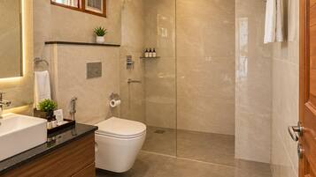 Un baño moderno con techo de madera, cabina de ducha de vidrio, inodoro blanco y tocador con lavamanos y espejo.