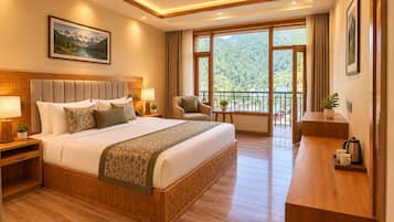 A hotel room with a large bed, a desk, a chair, and a balcony with a view of the mountains.