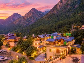 Un pueblo montañoso con casas tradicionales, una carretera pavimentada y una vista despejada de las colinas circundantes.