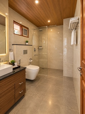 Un baño moderno con techo de madera, cabina de ducha de vidrio, inodoro blanco y tocador con lavamanos y espejo.