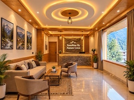Un hall de hotel con mostrador de recepción, zona de estar y amplios ventanales con vistas a la montaña.