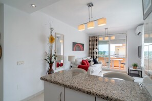 A modern living room with a large window, a dining area, and a kitchen. - Apartment in Nerja Near Torrecilla Beach (Nerja)