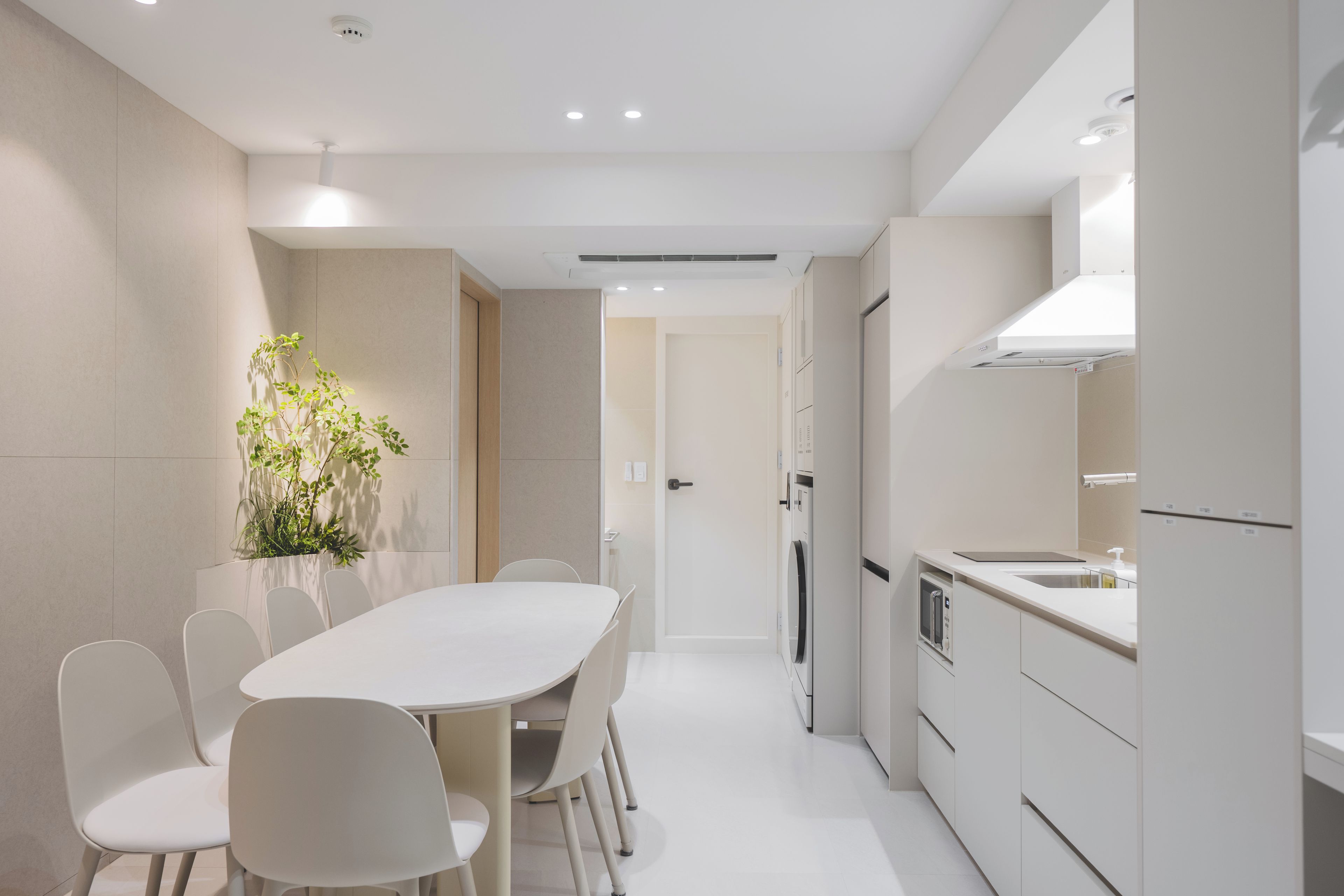 A modern kitchen with white cabinetry, a dining table with chairs, and a built-in oven.