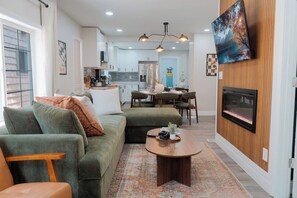 A modern living room with a green sofa, a coffee table, and a fireplace. - 5 Min to Downtown | Hot Tub • Arcade • Sleeps 11 (Indianapolis)