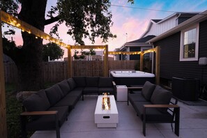 An outdoor patio with a sectional sofa, a fire pit, and string lights. - 5 Min to Downtown | Hot Tub • Arcade • Sleeps 11 (Indianapolis)