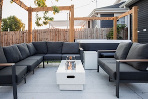 Eine Terrasse mit einer Eckcouch, einem kleinen Tisch und einem Whirlpool.