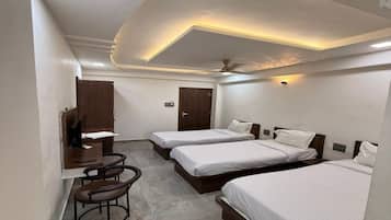 A hotel room with three beds, a desk, and a chair.