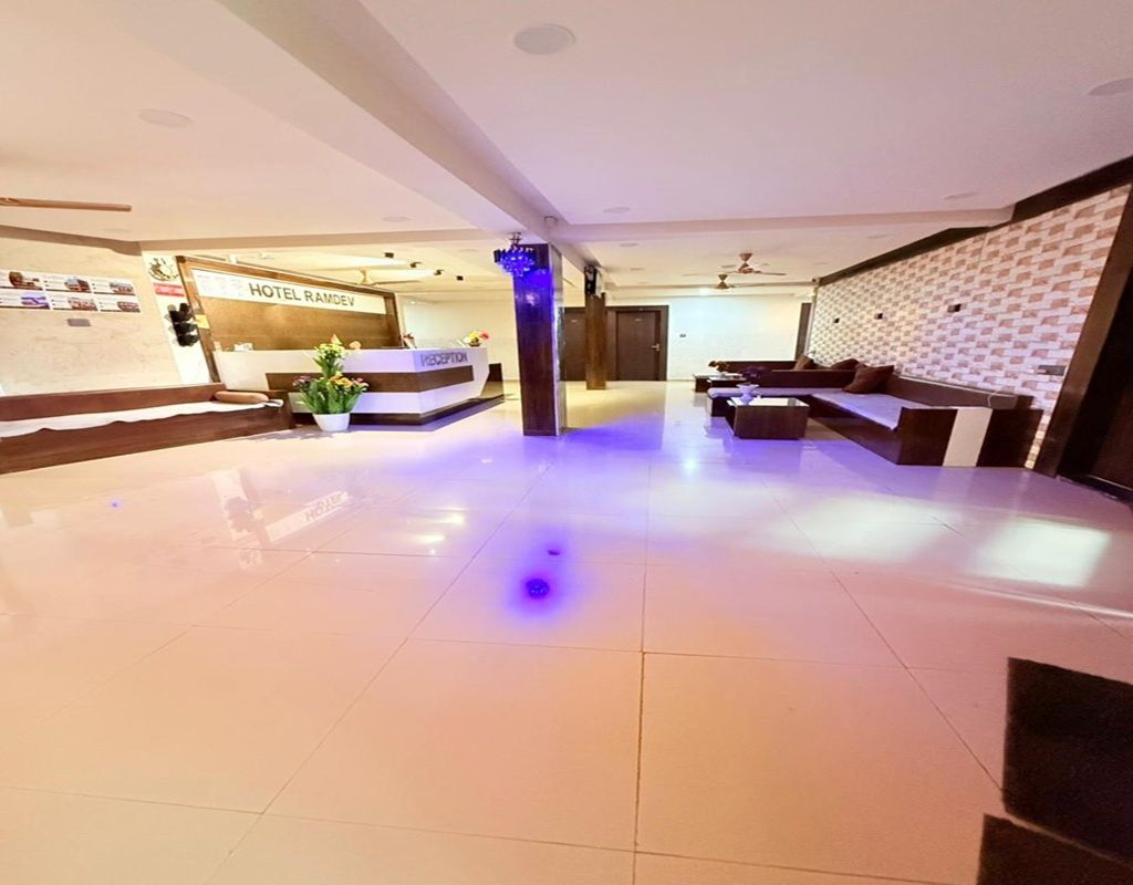 A hotel lobby with a reception desk, seating area, and a wall with a patterned design.
