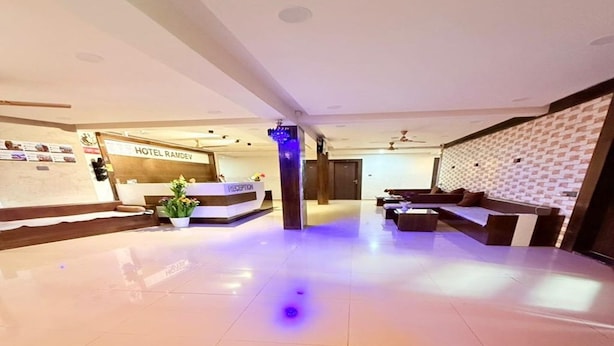 Un hall de hotel con mostrador de recepción, zona de estar y una pared con diseño decorativo.