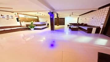 A hotel lobby with a reception desk, seating area, and a wall with a patterned design.