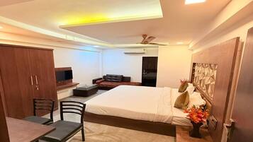 A modern bedroom with a bed, a desk, a chair, a wardrobe, and a television.