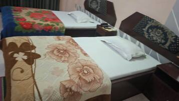 A hotel room with two beds, each with a distinct floral bedspread.