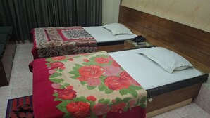 Dos camas individuales con cubrecamas florales, una mesita de noche con teléfono y una cortina al fondo.