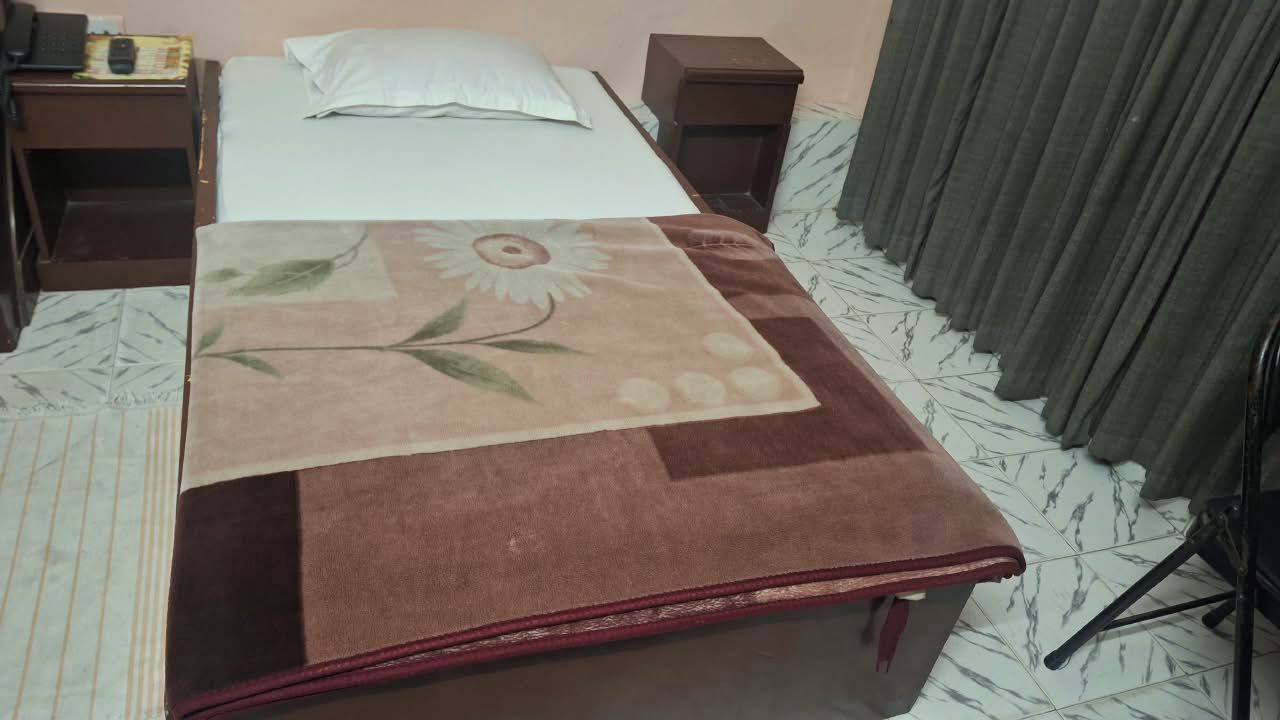 A hotel room with a bed, a nightstand, a desk, and a chair.