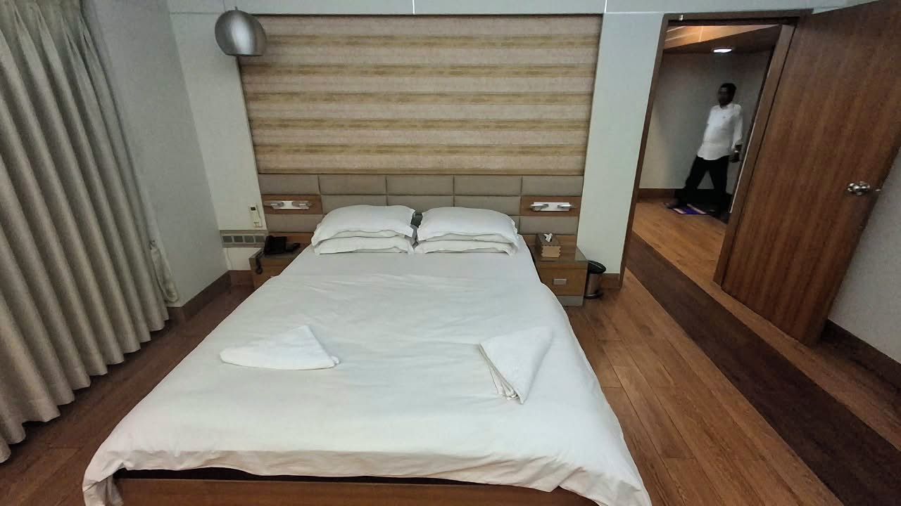 A hotel room with a bed, bedside tables, a wardrobe, and a mirror.