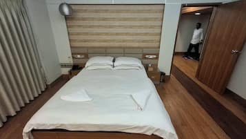 A hotel room with a bed, bedside tables, a wardrobe, and a mirror.