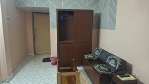 Une pièce comprenant un canapé, une chaise en bois, une armoire et une porte.