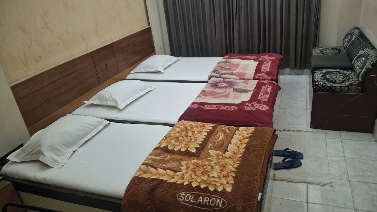 A room with two beds, a sofa, and a pair of slippers on the floor.
