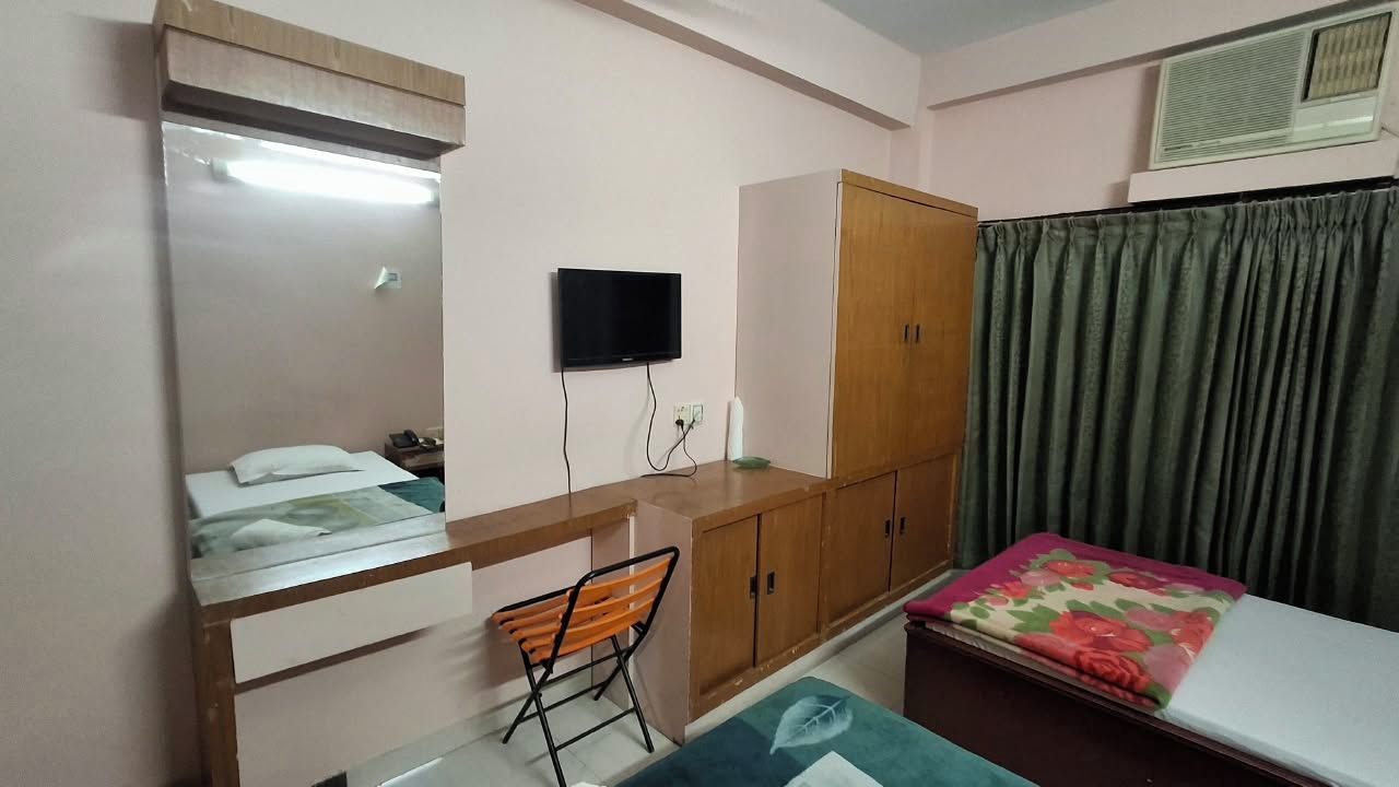 A bedroom with a bed, a desk, a chair, a wardrobe, and a television.